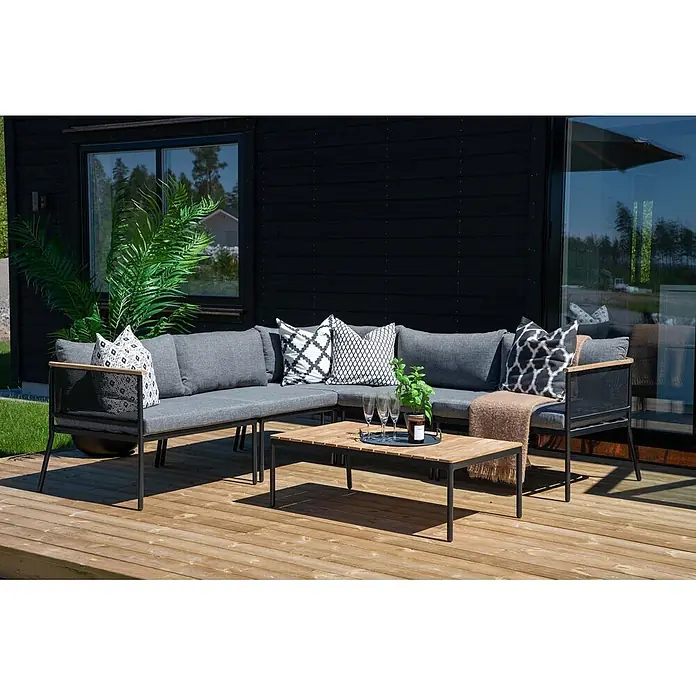 Ebuy24 Loungemöbel-Set Nettan - 2 -tlg., Stahl Teak, Schwarz - L-förmige Outdoor-Lounge-Sitzgruppe mit grauen Kissen, schwarzen Gestellen, Holzdetails und passendem Couchtisch auf einer Holzterrasse.
