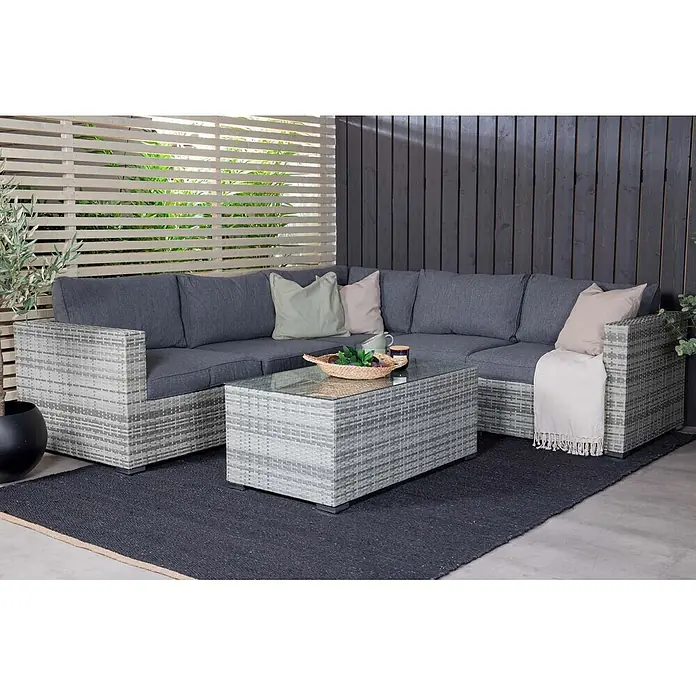 Ebuy24 Loungemöbel-Set Amazon - 2 -tlg., Korbmöbel, Grau - Graue Korbmöbel-Eckloungegruppe für den Außenbereich mit dunkelgrauen Polstern und Couchtisch mit Glasplatte auf einer Terrasse.