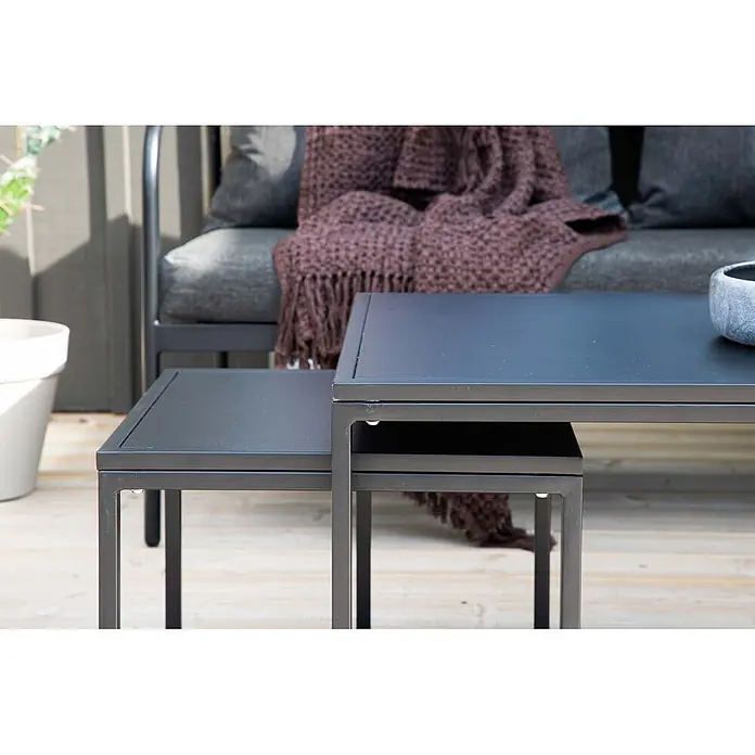 Ebuy24 Loungemöbel-Set Sopot - 4 -tlg., Stahl, Schwarz - Zwei dunkelgraue Beistelltische für den Außenbereich auf Holzterrasse neben einem Sofa.