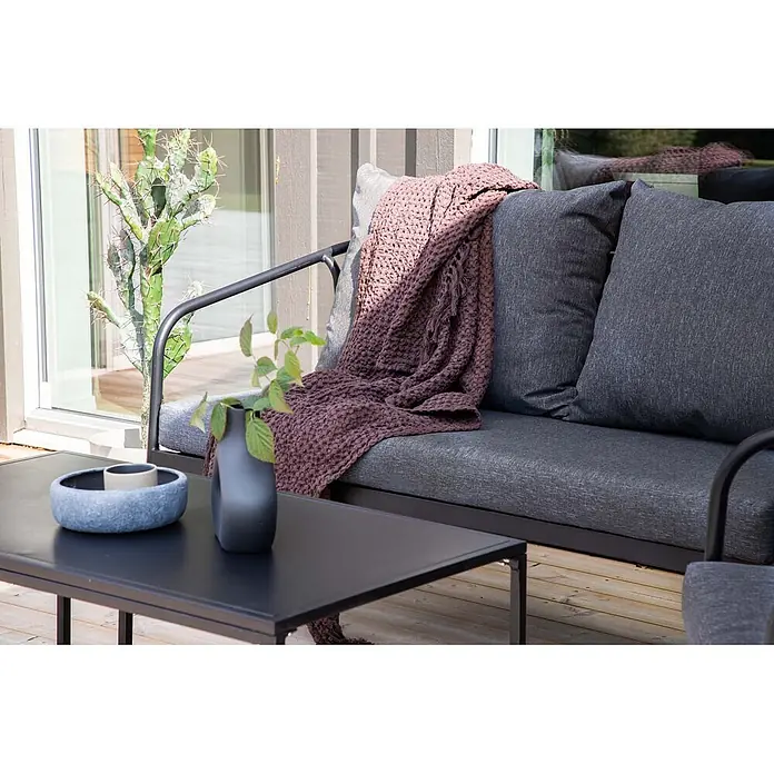 Ebuy24 Loungemöbel-Set Sopot - 4 -tlg., Stahl, Schwarz - Dunkelgraues Outdoor-Lounge-Sofa mit Kissen und einer pflaumenfarbenen Decke auf einer Holzterrasse, neben einem schwarzen Couchtisch.