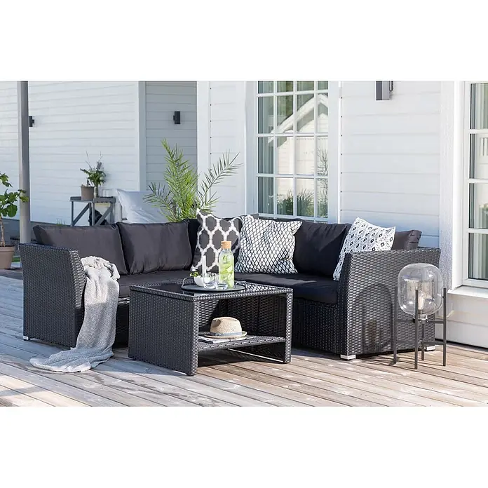 Ebuy24 Loungemöbel-Set Haiti - 4 -tlg., Korbmöbel, Schwarz - Schwarze Rattan-Gartenloungegarnitur mit schwarzen Kissen und passendem Couchtisch auf Holzterrasse.