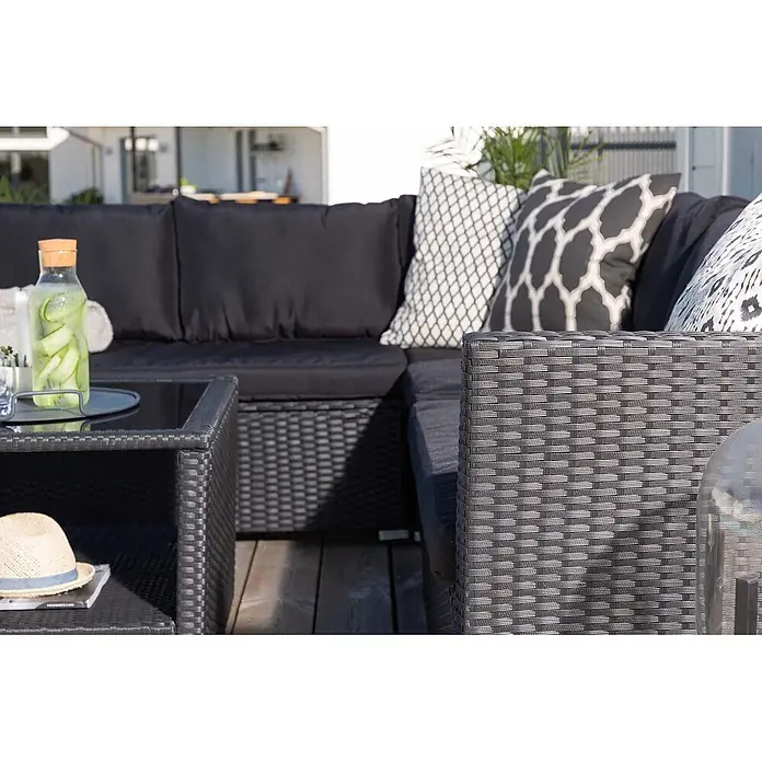 Ebuy24 Loungemöbel-Set Haiti - 4 -tlg., Korbmöbel, Schwarz - Dunkelgraues geflochtenes Outdoor-Ecksofa mit schwarzen Kissen, gemusterten Zierkissen und passendem Tisch.