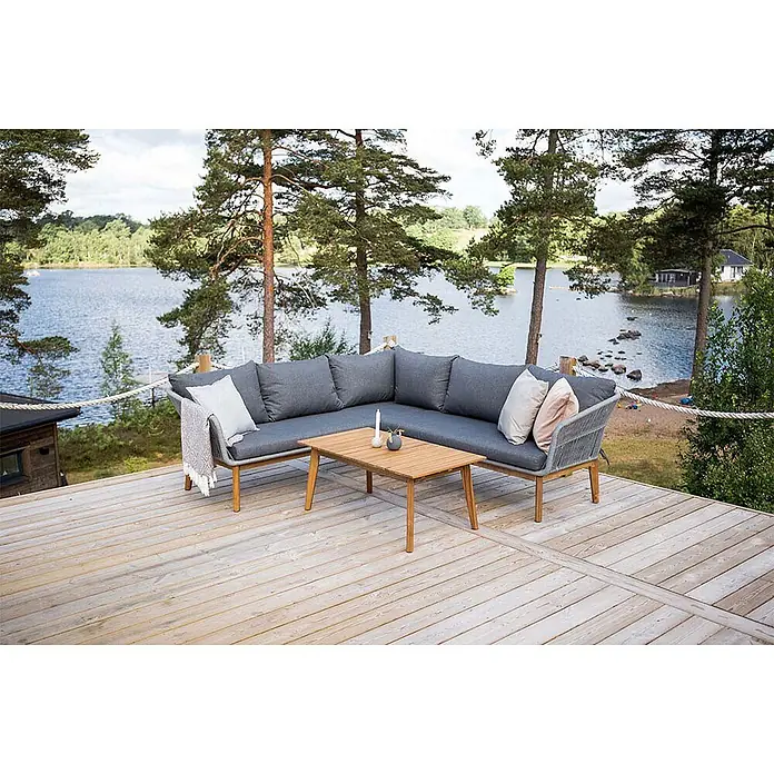 Ebuy24 Loungemöbel-Set Chania - 2 -tlg., Polyester Seil Akazie, Grau - Graues L-förmiges Outdoor-Sofa mit Holzrahmen und Couchtisch auf einer Terrasse am See.