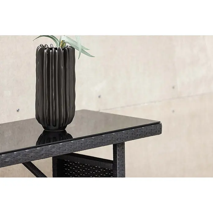 Ebuy24 Garten-Beistelltisch Padova - L x B x H: 40 x 120 x 74 cm, Korbmöbel, Stapelbar, Sonstige, Schwarz - Schwarze Keramikvase mit Pflanze auf einem schwarzen Glastisch mit Rattan-Design.