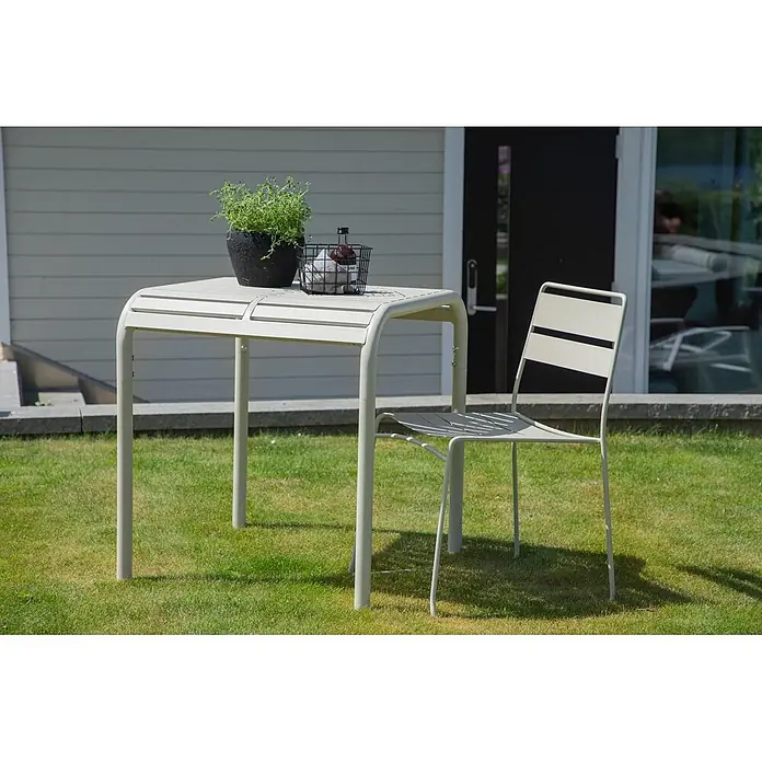Ebuy24 Garten-Beistelltisch Borneo - L x B x H: 70 x 70 x 75 cm, Aluminum, Stapelbar, Beige - Helles Metall-Gartentisch- und Stuhlset. Eine Topfpflanze und eine Flasche stehen auf dem Tisch.