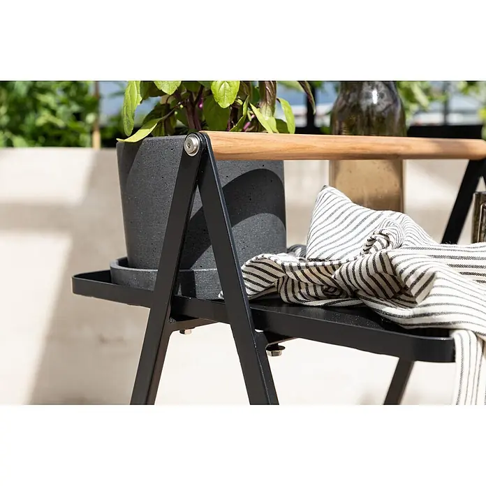 Ebuy24 Garten-Beistelltisch Clarin - L x B x H: 45 x 45 x 59 cm, Stahl, Teak, Stapelbar, Sonstige, Schwarz - Schwarzer Metall-Pflanzenständer mit Holzgriff, mit Betonkübel mit Pflanze und gestreiftem Handtuch.