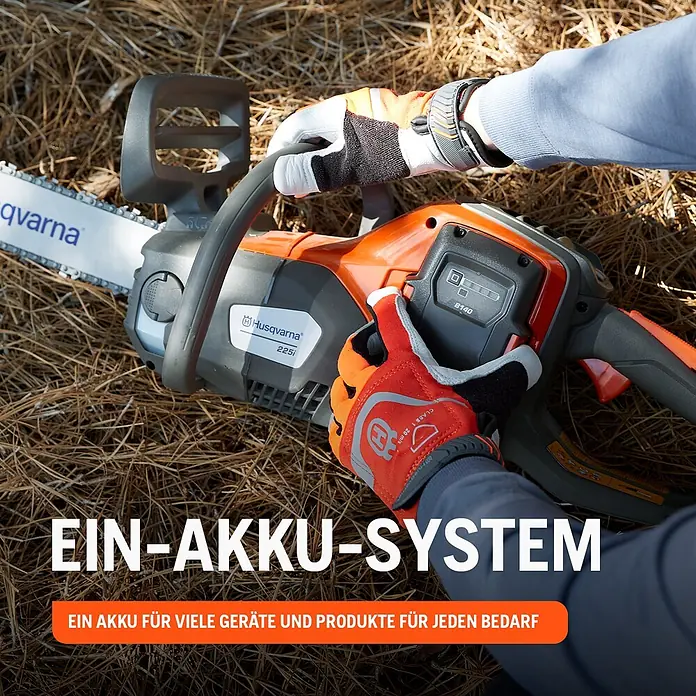 Husqvarna Akku-Kettensäge 225i - 36 V, Li-Ionen, Ohne Akku, Schwertlänge: 35 cm - Person mit orange-weißen Handschuhen hält eine grau-orange Husqvarna 225i Akku-Kettensäge, die ihr vielseitiges Akku-System hervorhebt.