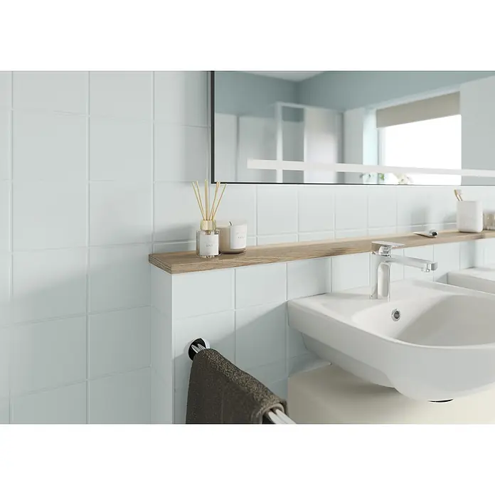 Alpina Buntlack Fliesenlack für Bad & Küche - Grün, Seidenglänzend, 0,75 l, Wasserbasiert - Modernes Bad mit weißem Keramikwaschbecken, Chromarmatur und Holzablage. Darauf Diffusor und Kerze, darunter dunkles Handtuch.