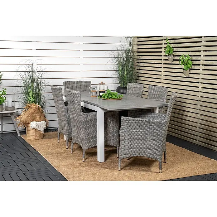 Ebuy24 Gartenstuhl Malin 2er-Set - 100 % Polyester, Aluminium, Rattan, Grau, B x T x H: 58 x 65 x 92 cm - Graues Outdoor-Essgruppe mit rechteckigem Tisch und sechs geflochtenen Stühlen auf einer Terrasse mit Jute-Teppich und Pflanzen.