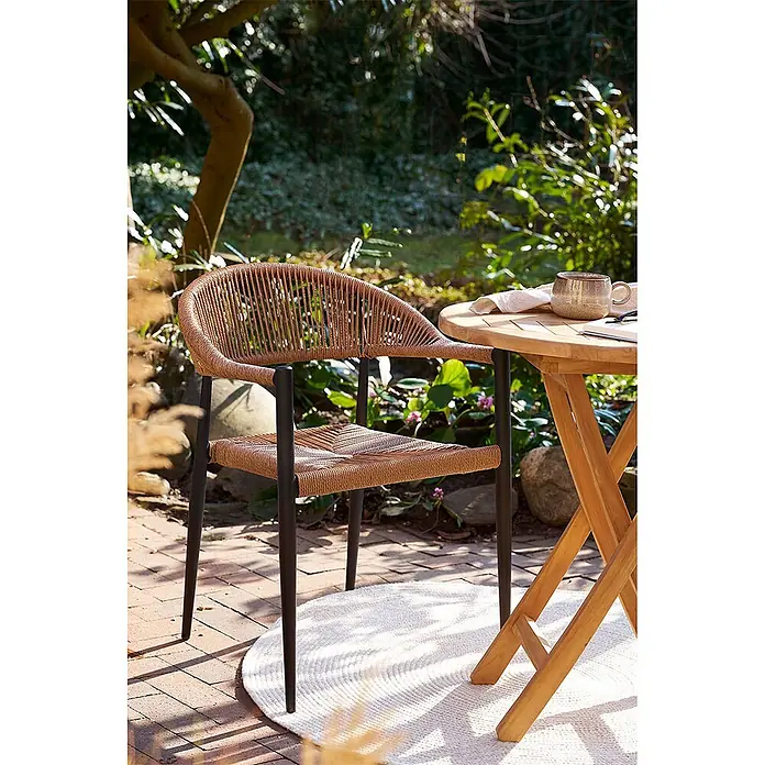 Ebuy24 Gartenstuhl Canari 2er-Set - PE Rattan, Aluminium, Natur, B x T x H: 57 x 60 x 78 cm - Brauner geflochtener Outdoor-Stuhl mit schwarzen Beinen auf einer Terrasse neben einem Holztisch im Garten.