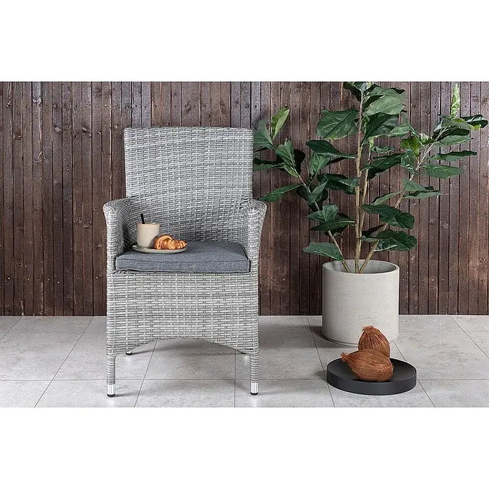 Ebuy24 Gartenstuhl Malin 2er-Set - Aluminium, Rattan, Polyester, Weiß, B x T x H: 58 x 65 x 92 cm - Grauer Outdoor-Esszimmerstuhl aus Rattan mit grauem Kissen, darauf eine Tasse Kaffee und ein Croissant.
