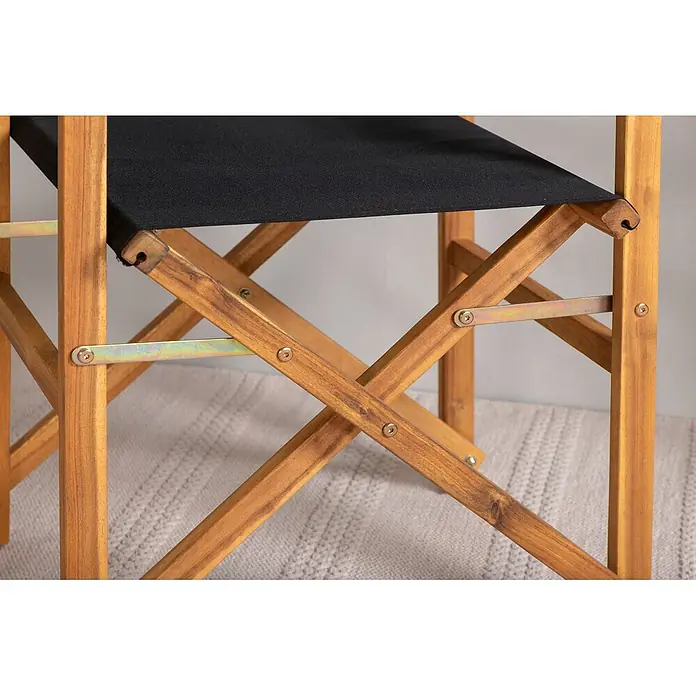 Ebuy24 Gartenstuhl Marion 2er-Set - 2 Stk., Polyester, Holz, B x T x H: 53 x 55 x 90 cm - Nahaufnahme eines klappbaren Regiestuhls aus Holz mit schwarzer Stoffbespannung und X-Gestell.