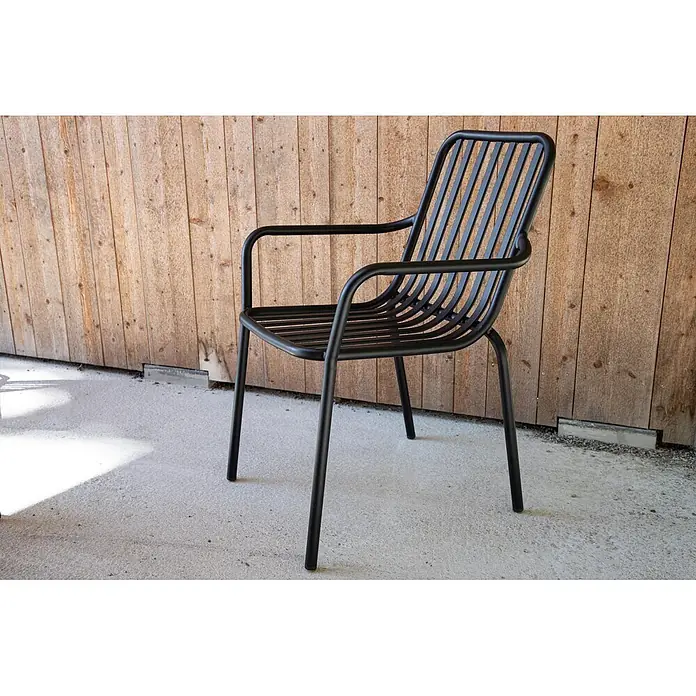 Ebuy24 Gartenstuhl Peking 2er-Set - Aluminum, Schwarz, B x T x H: 57 x 64 x 85 cm - Schwarzer Metallstuhl mit Lattenrückenlehne und Sitzfläche, mit Armlehnen, auf Beton vor einer Holzwand.
