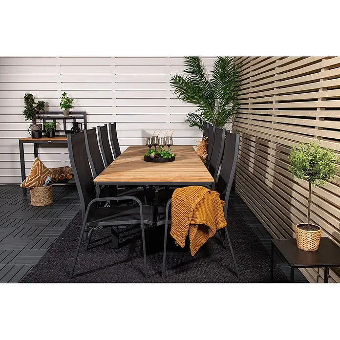 Ebuy24 Gartenstuhl Copacabana 2er-Set - 30 % Polyester, 70 % PVC, Aluminium, Textil, Schwarz, B x T x H: 57 x 65 x 110 cm - Eine Outdoor-Essgruppe mit Holztisch, dunklen Stühlen und schwarzem Teppich auf einer Terrasse.