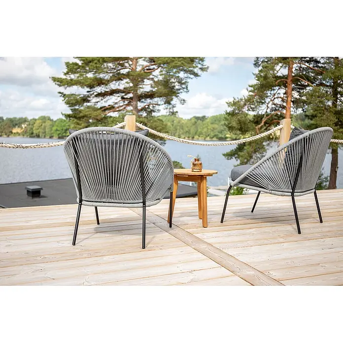 Ebuy24 Gartensessel Lindos 2er-Set - 2 Stk., Stahl, Grau, B x T x H: 73 x 85 x 78 cm - Zwei graue Outdoor-Loungesessel und ein kleiner Holztisch auf einer Terrasse am See.