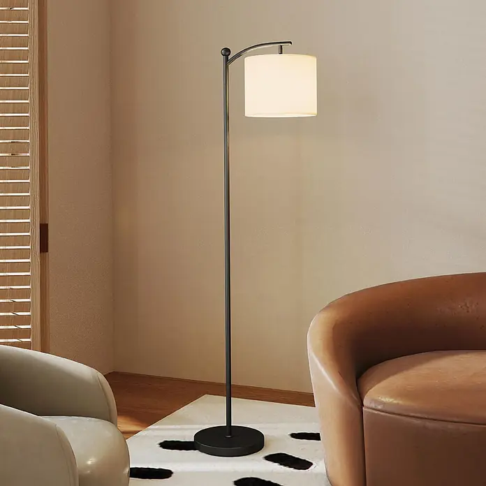 Homcom Stehleuchte - 9 W, Höhe: 159,6 cm, Schwarz, Cremeweiß, E27 - Hohe, schwarze Bogen-Stehlampe aus Metall mit weißem Zylinderschirm, beleuchtet einen Raum. Steht neben einem braunen Sessel auf einem gemusterten Teppich.