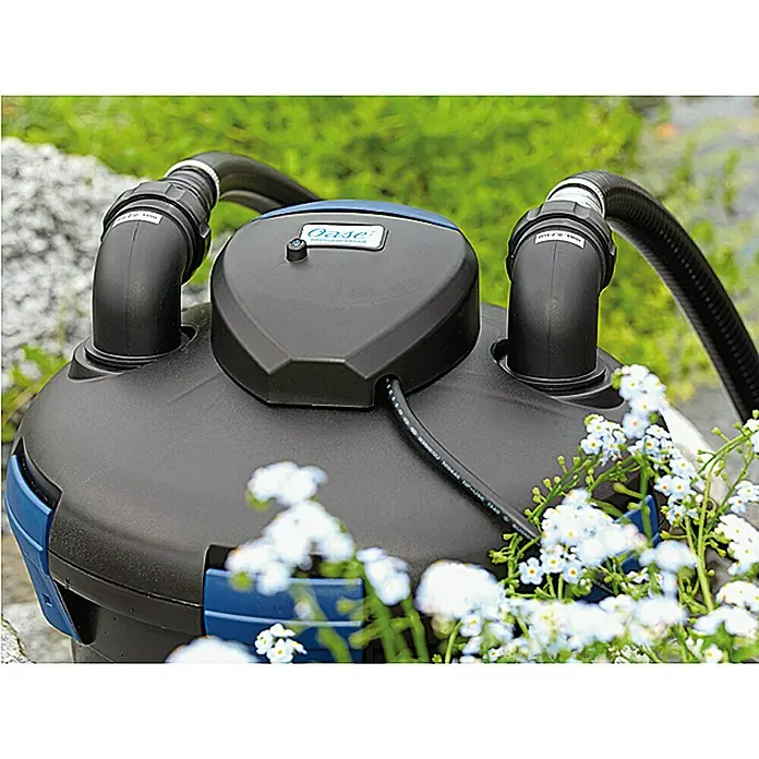 Oase Druckfilter BioPress Set 4000 - 25 W, Teichgröße: 4 m³ - Oase Teichfilter im Außenbereich mit Blumen im Vordergrund. Optimal für klare Teiche und gesunde Wasserqualität.