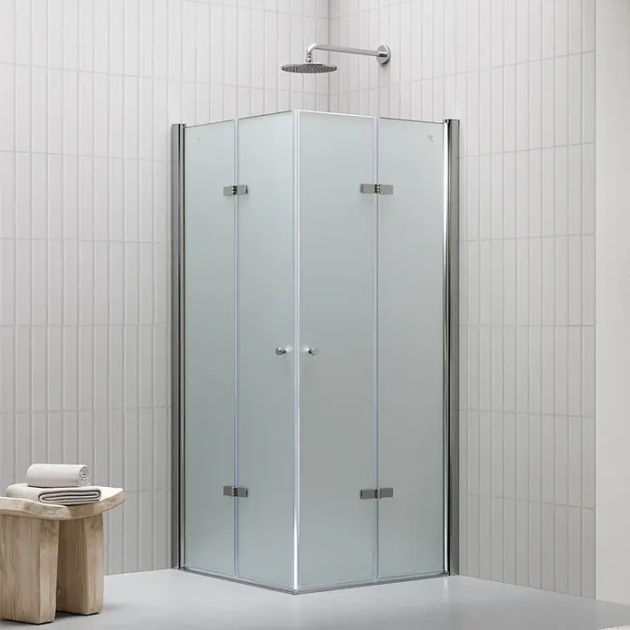 i-flair Eckdusche DK99FR105x80 - Beschichtet, Silber, Stärke: 6 mm - Eckduschkabine aus Milchglas mit Chromarmaturen in einem gefliesten Bad, dazu ein Holzschemel mit Handtüchern.