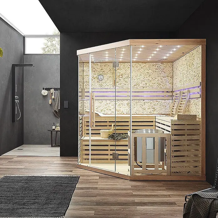 Home Deluxe Elementsauna SKYLINE BIG XL KUNSTSTEINWAND - Elektroofen, Steuerung Ofen: Integriert, L x B x H: 200 x 200 x 210 cm - Moderne Holz-Glas-Sauna mit Strukturwänden, LED-Beleuchtung und Bänken, in einem modernen Spa-Badezimmer neben einer Dusche.