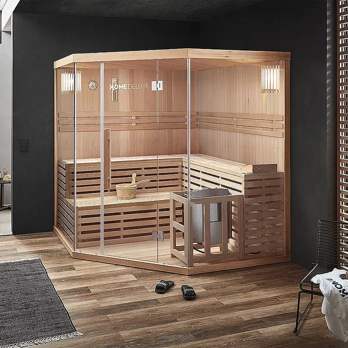 Home Deluxe Elementsauna SKYLINE BIG XL - Elektroofen, Steuerung Ofen: Integriert, L x B x H: 200 x 200 x 210 cm - Moderne Ecksaunakabine mit hellem Holzinterieur und Glasfront, ausgestattet mit Bänken und Heizgerät, in stilvoller Raumumgebung.