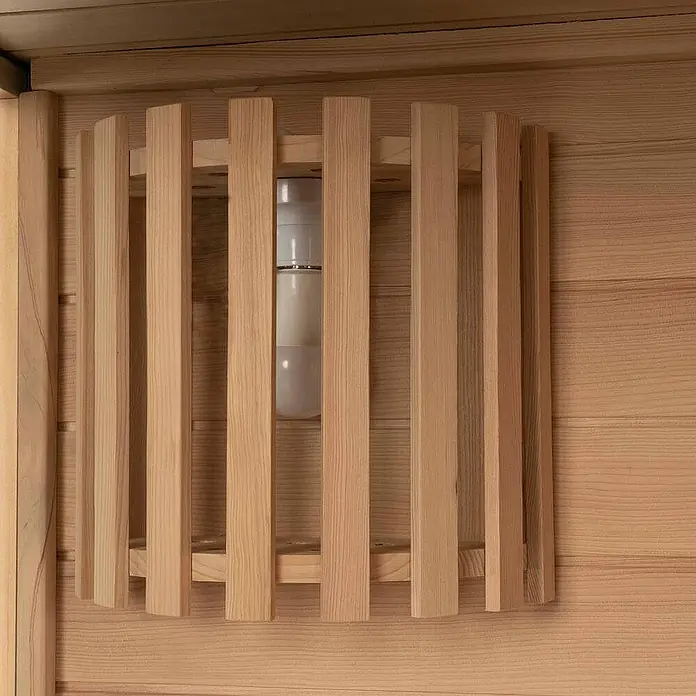 Home Deluxe Elementsauna SKYLINE BIG XL - Elektroofen, Steuerung Ofen: Integriert, L x B x H: 200 x 200 x 210 cm - Eine Saunaleuchte mit schützendem Holzlamellenschutz, an einer hellen Holzwand montiert.