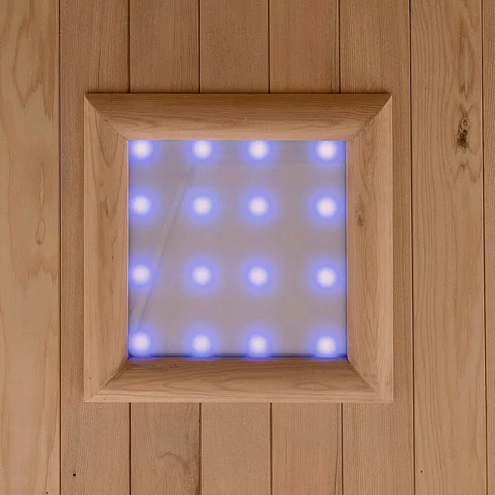 Home Deluxe Infrarotkabine SAHARA L -  - Quadratisches Lichtpaneel mit Holzrahmen und blau leuchtenden LEDs, in eine Holzwand integriert.