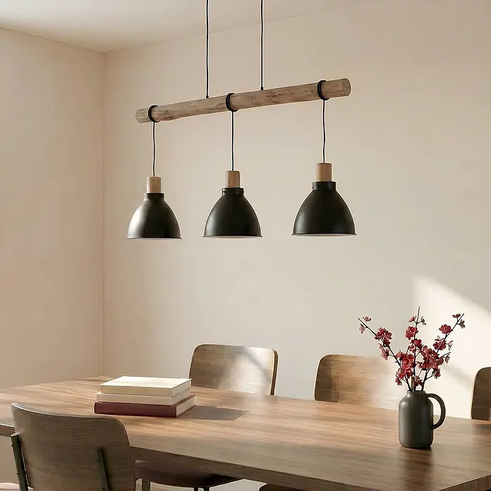 Lindby Pendelleuchte Trebale - L x B x H: 123 x 28 x 28 cm, schwarz, Schwarz, Holz hell, E27 - Dreiflammige Pendelleuchte mit schwarzen Metallschirmen und Holzbalken über einem Esstisch.