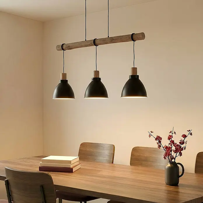Lindby Pendelleuchte Trebale - L x B x H: 123 x 28 x 28 cm, schwarz, Schwarz, Holz hell, E27 - Dreiflammige Pendelleuchte mit Holzstange und schwarzen Metallschirmen, beleuchtet einen Esstisch.