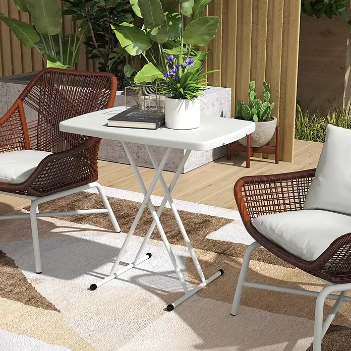 Outsunny Campingtisch - L x B x H: 76 x 50 x 74 cm, Kunststoff, Metall, Weiß, Klappbar - Weißer Klapptisch und braune Korbstühle mit weißen Kissen auf einer Terrasse.