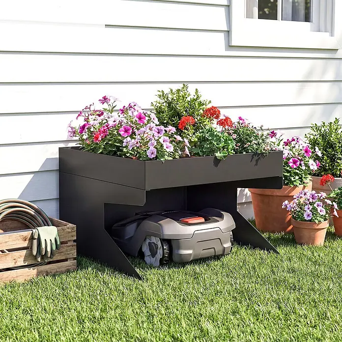 Outsunny Mähroboter-Garage - Schwarz, Rasenmähroboter - Schwarzes Metall-Pflanzgefäß und Mähroboter-Garage, mit bunten Blumen bepflanzt.