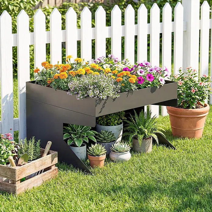 Outsunny Mähroboter-Garage - Schwarz, Rasenmähroboter - Dunkelgraues Hochbeet aus Metall mit bunten Blumen, platziert in einem Garten neben einem weißen Lattenzaun.