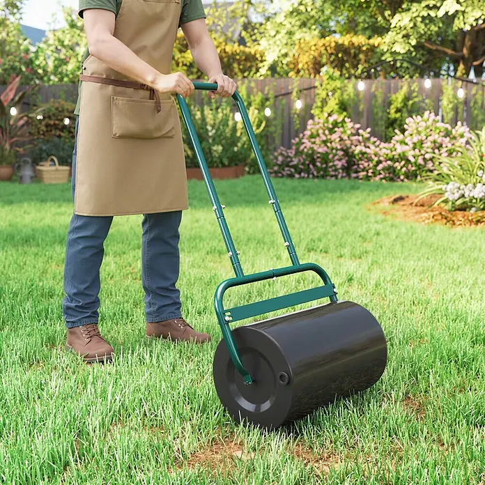 Outsunny Rasenwalze - Passend für: frisch gesäten Rasen und unebene Stellen, Arbeitsbreite: 50 cm, Dunkelgrün - Person nutzt grüne Rasenwalze mit schwarzer Trommel, um Rasen zu ebnen.