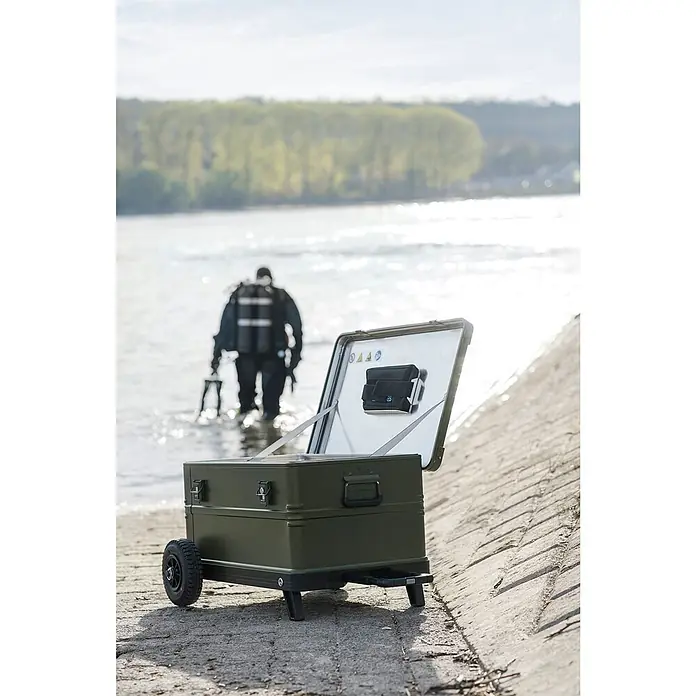 Zarges Aufbewahrungsbox K 424 XC Mobil Universal Alu Box 105l -  - Dunkelgrüner Rollkoffer mit geöffnetem Deckel am Wasserufer, Taucher im Hintergrund.