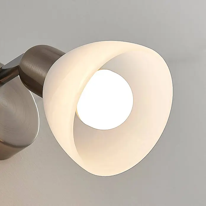 Lindby Wandleuchte Paulina - alu / grau / zink, E14 - Moderne Wandleuchte mit gebürstetem Metallarm und einzigartigem gebogenem weißem Opalglasdiffusor, der eine leuchtende Birne zeigt.