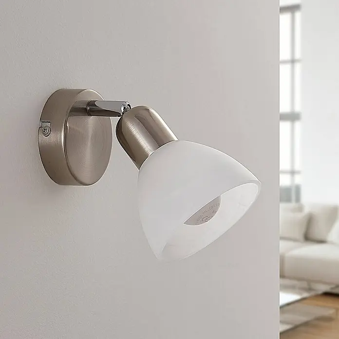Lindby Wandleuchte Paulina - alu / grau / zink, E14 - Wandstrahler aus gebürstetem Metall mit verstellbarem Arm und mattweißem Glasschirm, an einer Wand montiert.