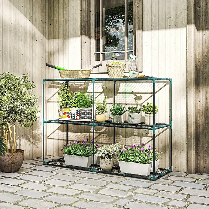 Outsunny Gewächshaus-Regal - 143 x 48 x 100 cm, Dunkelgrün - Zweistöckiges dunkelgrünes Metall-Pflanzenregal mit Töpfen und Gartengeräten vor einer Holzwand.