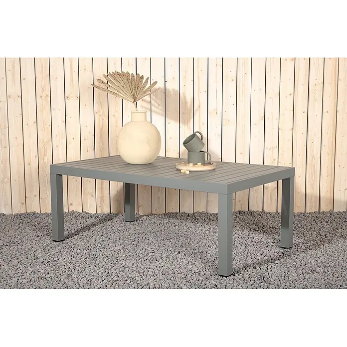 Ebuy24 Garten-Loungetisch Copacabana - L x B x H: 70 x 120 x 45 cm, Ø x H: 70 x 45 cm, Aluminum, Khaki, Stapelbar - Grauer rechteckiger Latten-Gartentisch, im Freien auf Kies mit Vase und Tassen dekoriert.