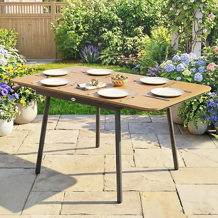 Outsunny Gartentisch - L x B x H: 140 x 80 x 75 cm - Gartentisch mit Holzoptik-Platte und dunklen Beinen, gedeckt auf einer Terrasse im Garten.