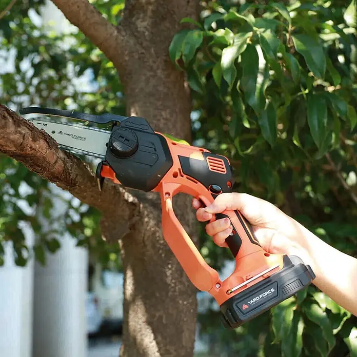 Yard Force Einhand-Akku-Kettensäge LS C13 - 2 Ah, 1 Akku - Orange-schwarze Akku-Minikettensäge schneidet einen Ast.
