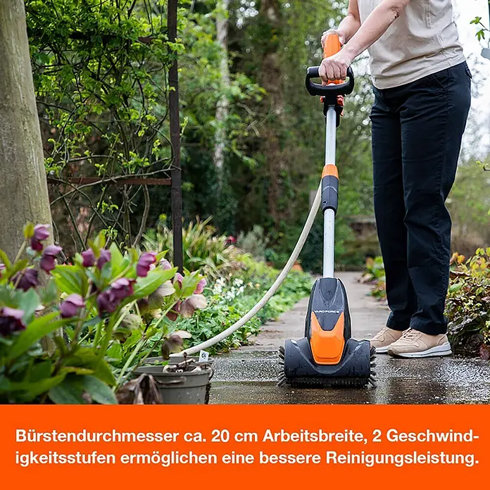 Yard Force Akku-Reinigungsbürste LW CPC1 - 20 V, 1 Akku, 4 Ah - Person reinigt eine Terrasse mit einem orange-schwarzen elektrischen Bürstenreiniger, der an einen Schlauch angeschlossen ist und eine Arbeitsbreite von 20 cm hat.
