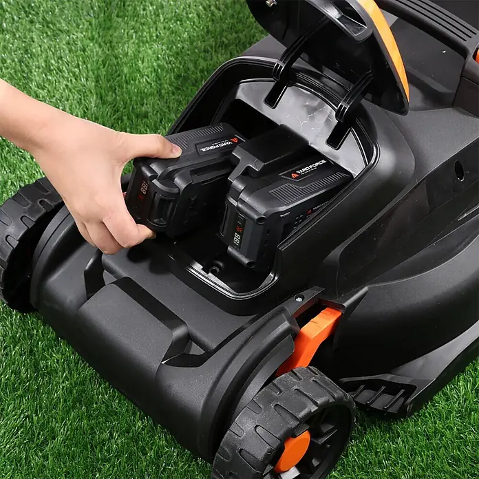 Yard Force Akku-Rasenmäher LM C37 - 40 V, 1 Akku, 4 Ah, Schnittbreite: 370 mm - Hand steckt schwarzen Akku mit LED-Anzeige in schwarzen und orangefarbenen Akku-Rasenmäher.