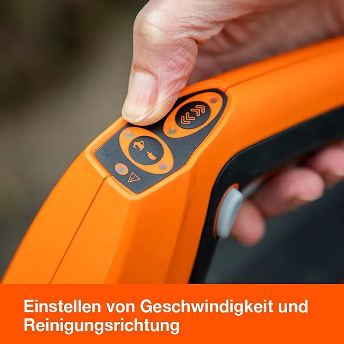 Yard Force Akku-Reinigungsbürste LW CPC1 - 20 V, 1 Akku, 4 Ah - Hand stellt Einstellungen an orange-schwarzem Handgerät mit Geschwindigkeits- und Richtungssymbolen ein.