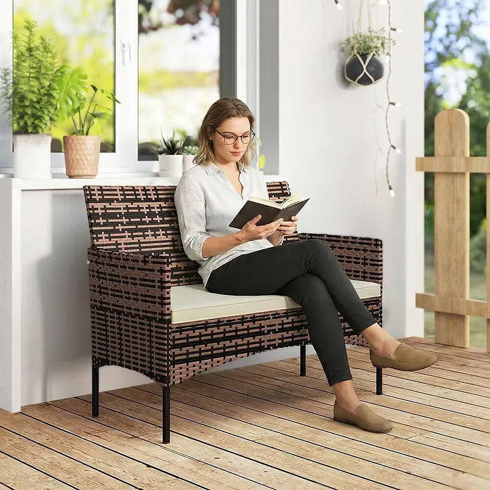 Outsunny Loungesofa - Stahl, PE-Rattan, Khaki - Dunkelbraune und schwarze Rattan-Sitzbank mit hellem Kissen, auf einer Holzterrasse genutzt.