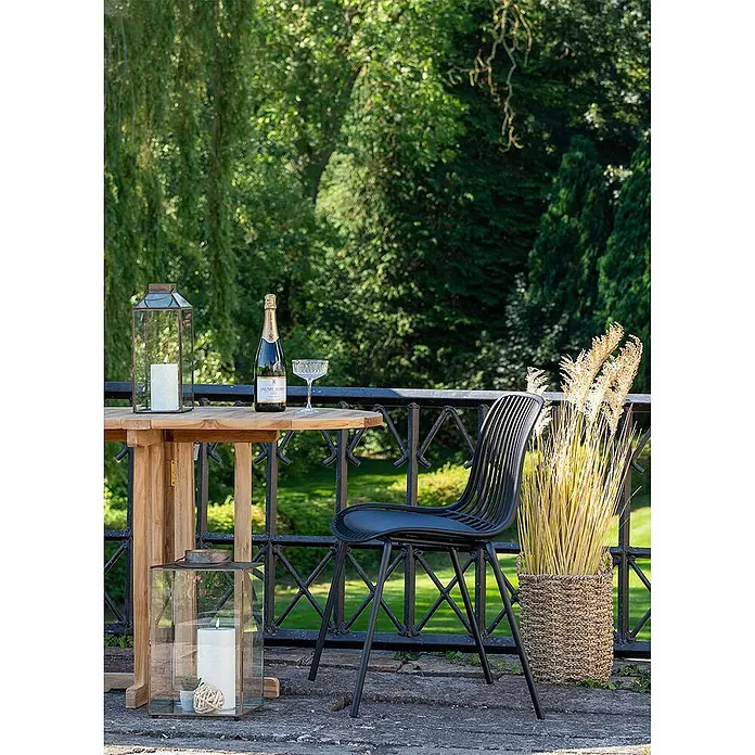 Ebuy24 Gartenstuhl Branson 4er-Set - 4 Stk., PP, Stahl, Schwarz, B x T x H: 47 x 55 x 82 cm - Schwarzer Metallstuhl mit Lattenrücken auf einer Terrasse neben einem Holztisch, ideal für den Außenbereich.