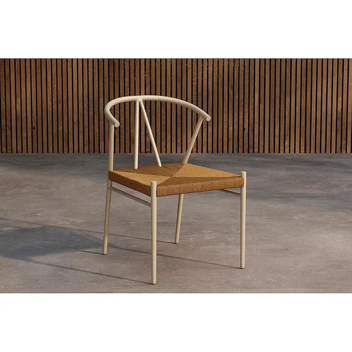 Ebuy24 Gartenstuhl Alfons - 1 Stk., Stahl, Beige, B x T x H: 55 x 58 x 74 cm - Heller beigefarbener Stuhl mit geschwungener Rückenlehne und natürlichem Geflechtsitz, vor einer Holzwand und Beton.