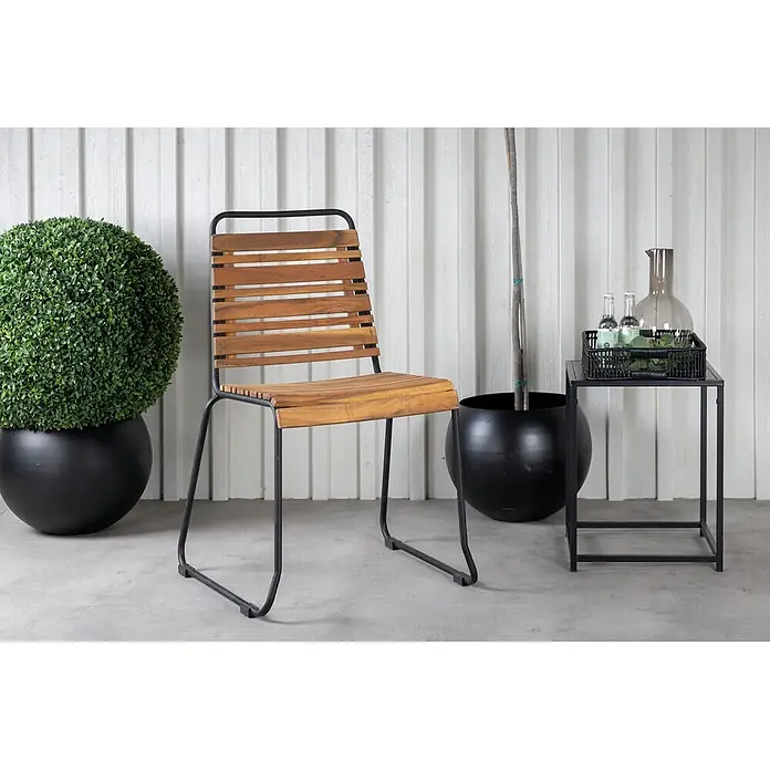 Ebuy24 Gartenstuhl Bois 4er-Set - 4 Stk., Stahl, Holz, Akazie Dekor, B x T x H: 57 x 59 x 86 cm - Holzlamellenstuhl mit schwarzem Metallgestell in Außenumgebung mit Pflanzgefäßen und Beistelltisch.