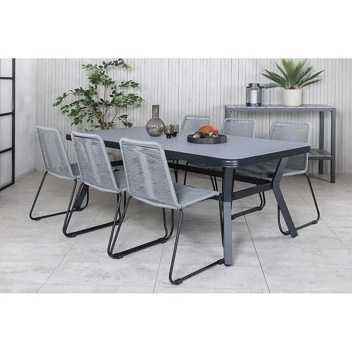 Ebuy24 Gartenstuhl Lindos 4er-Set - 4 Stk., 100 % Polyester (Seil), Stahl, Grau - Grauer Outdoor-Esstisch mit sechs hellgrauen Seilstühlen, platziert in einer modernen Terrassenumgebung mit Dekoration.