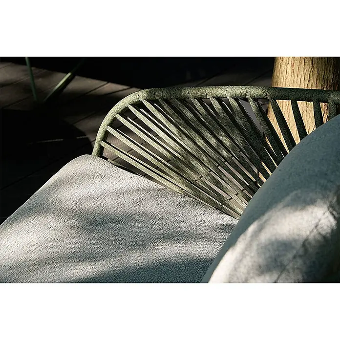 Ebuy24 Loungemöbel-Set Novella - 5 -tlg., Schaum, Polyester, Stahl, Grau - Nahaufnahme eines Outdoor-Stuhls mit grünem geflochtenem Rücken und hellem Kissen im Sonnenlicht.