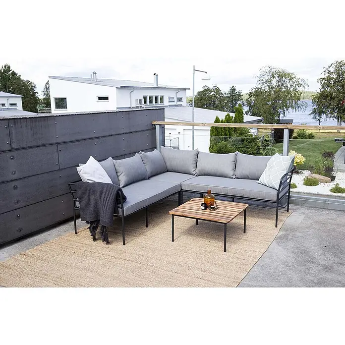 Ebuy24 Loungemöbel-Set Penh - 2 -tlg., Akazie, Grau - Graues L-förmiges Outdoor-Lounge-Sofa mit schwarzem Metallgestell und Holztisch auf einem Terrassenteppich, ideal zum Entspannen im Freien.