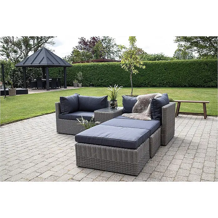 Ebuy24 Loungemöbel-Set Rosino - 3 -tlg., Polyrattan, Aluminium, Glas, Polyester, Grau - Grau geflochtene Gartenmöbel mit dunkelgrauen Polstern, auf einer gepflasterten Terrasse im Freien arrangiert.